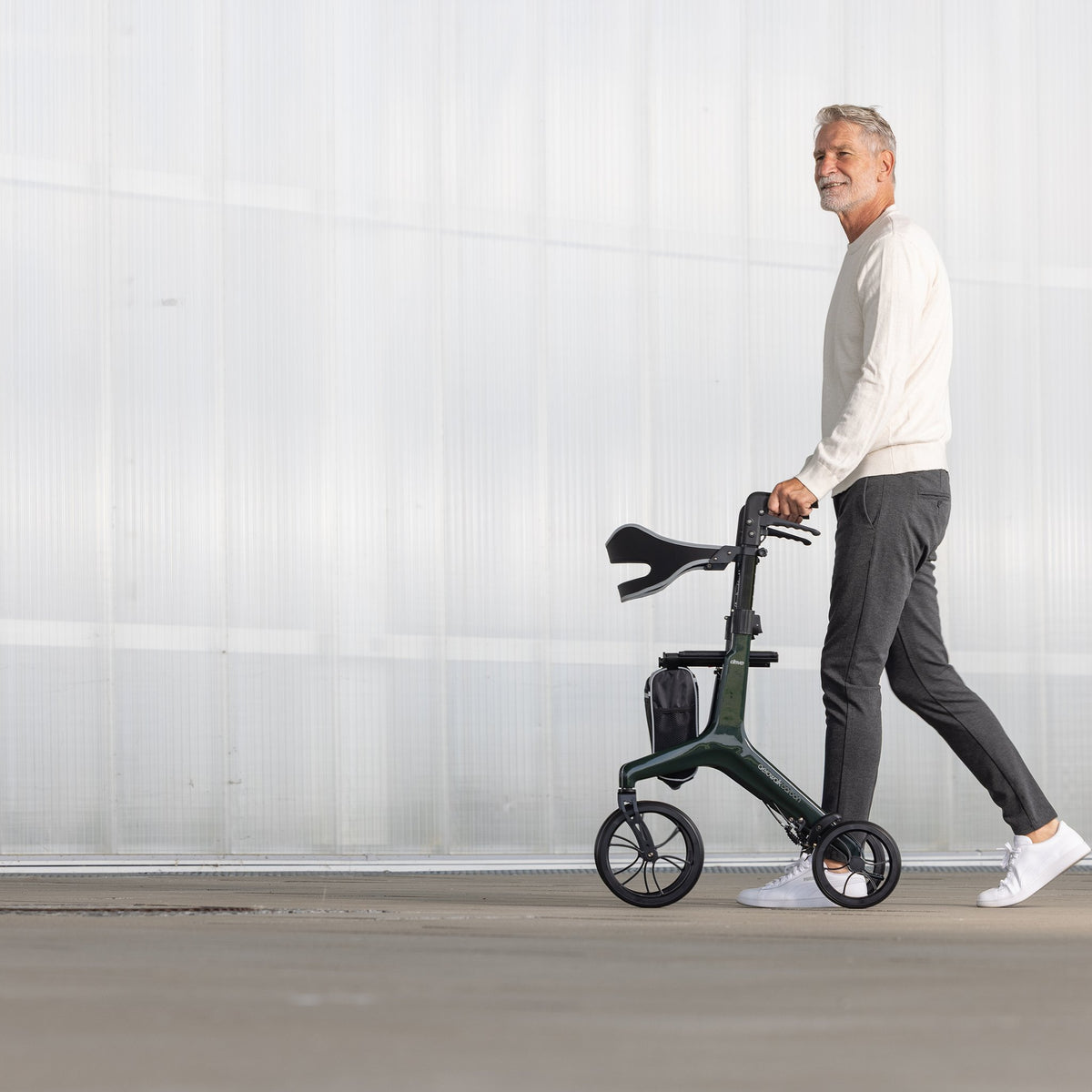 Mann geht mit dem Aero Walk Carbon Rollator in British Racing Green spazieren